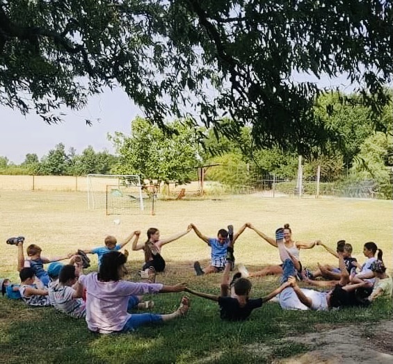 Kids sitting in the meadow in a circle having fun